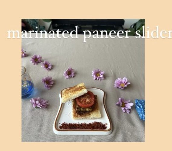 A marinated paneer slider stacked with tomato on toasted bread, plated on a small ceramic tray.