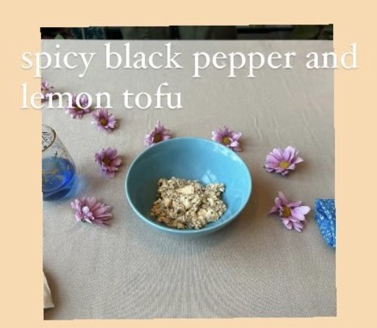 A blue bowl of spicy black pepper and lemon tofu on a linen tablecloth.