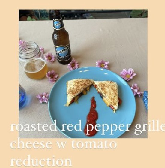 A roasted red pepper grilled cheese sandwich cut in half on a blue plate with a tomato reduction, next to a Blue Moon beer.