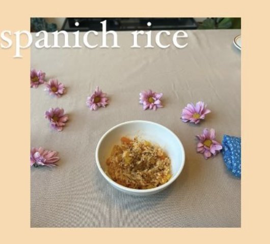 A white bowl of Spanish rice on a linen tablecloth surrounded by daisies.
