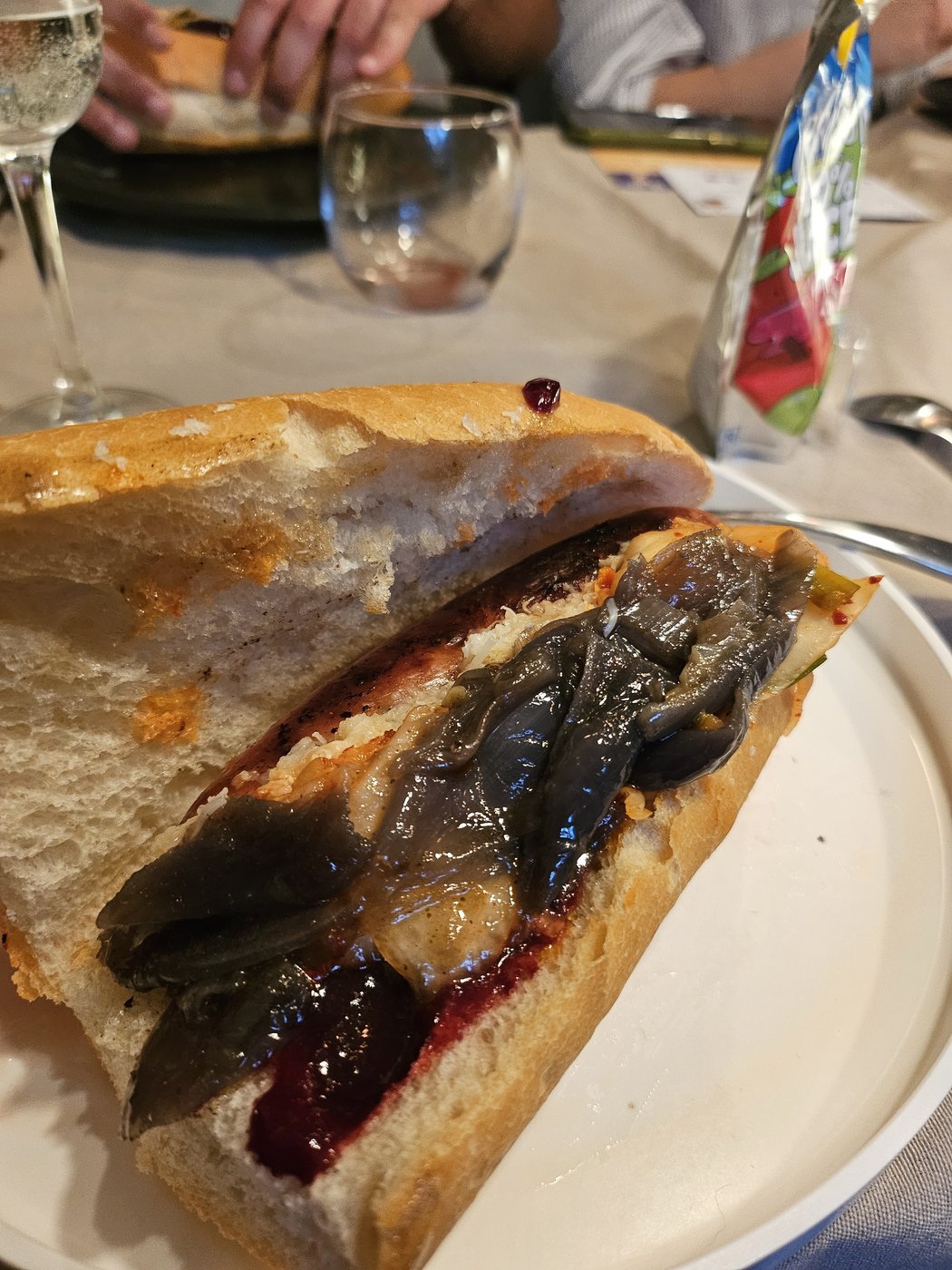 A sandwich on toasted bread with foil-cooked salmon and a dark berry compote.